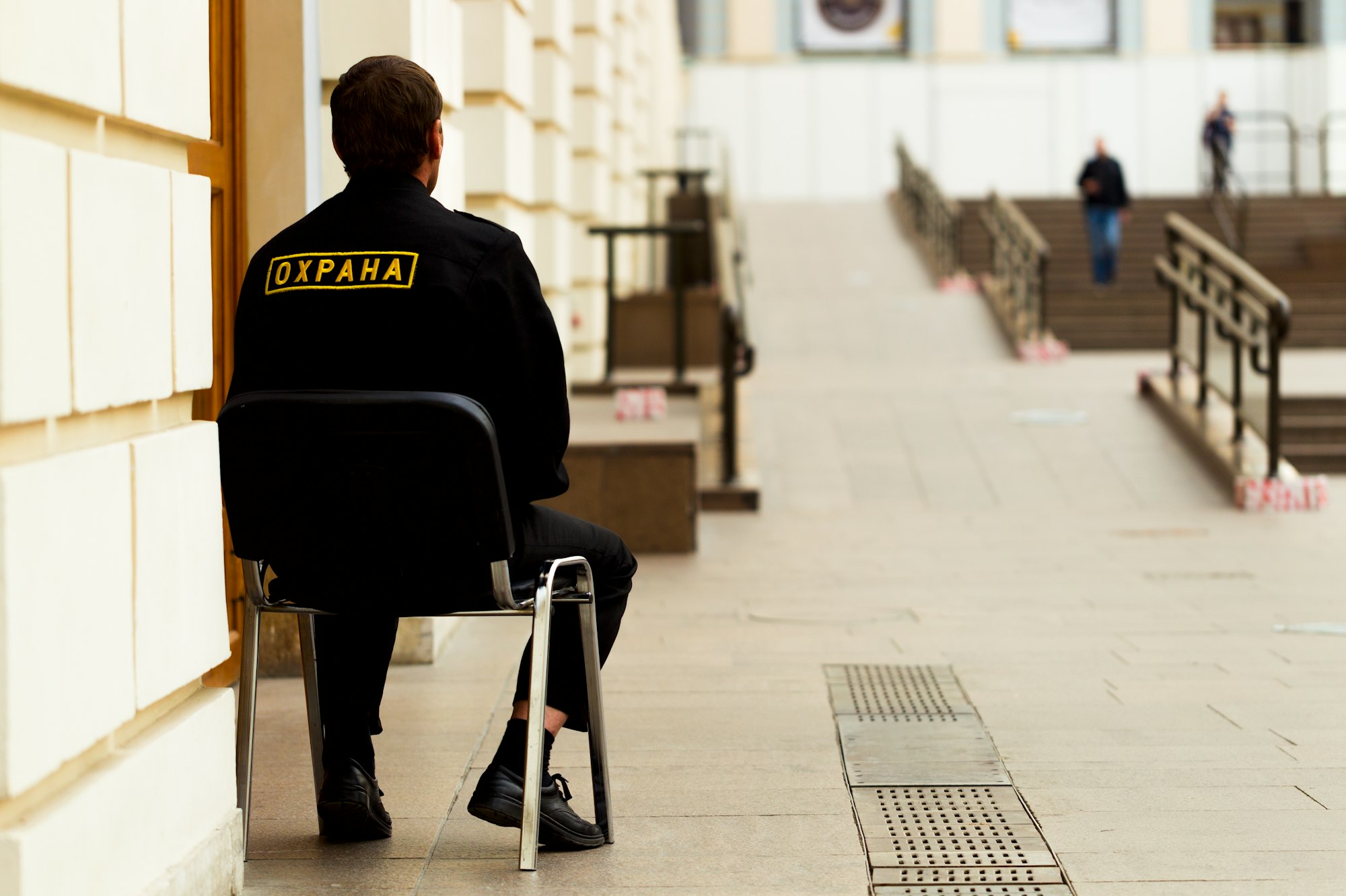 Security guard sitting on a chair at the entrance to the indoor